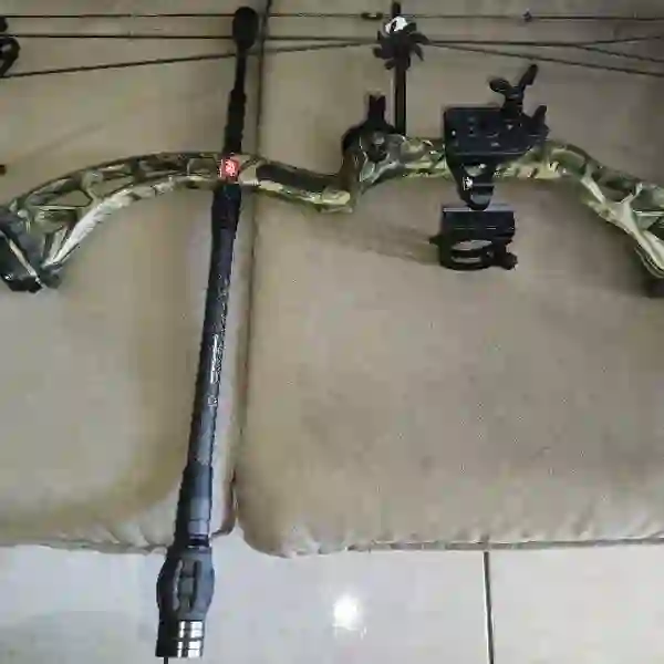 Black carbon bow stabilizer mounted on a camouflage compound bow riser — verified buyer photo (Brazil)